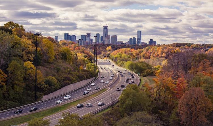 Connected cars generate data about driving and vehicle operation. Highway with cars driving to and from a large city